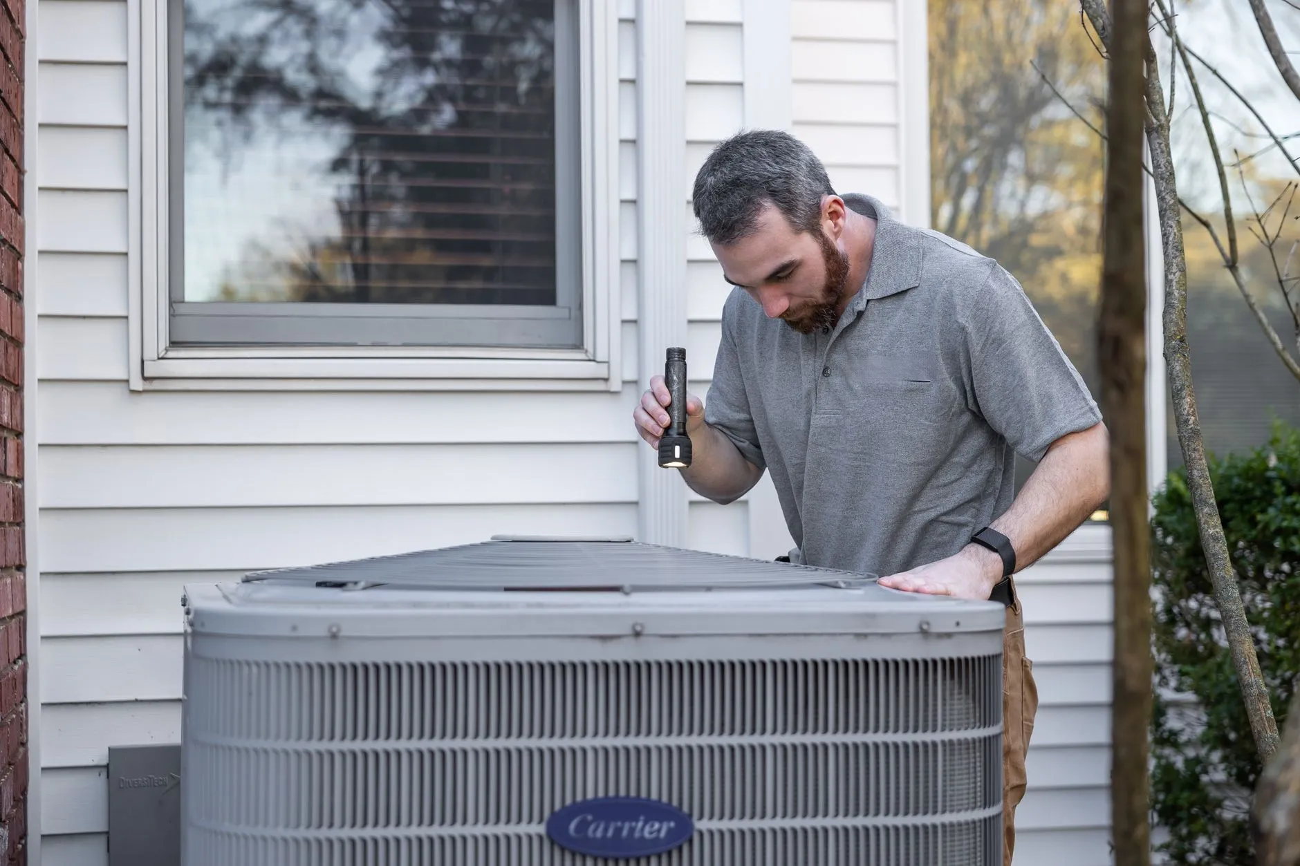 Professional technician repairing an outdoor air conditioning unit with gauges and tools.
