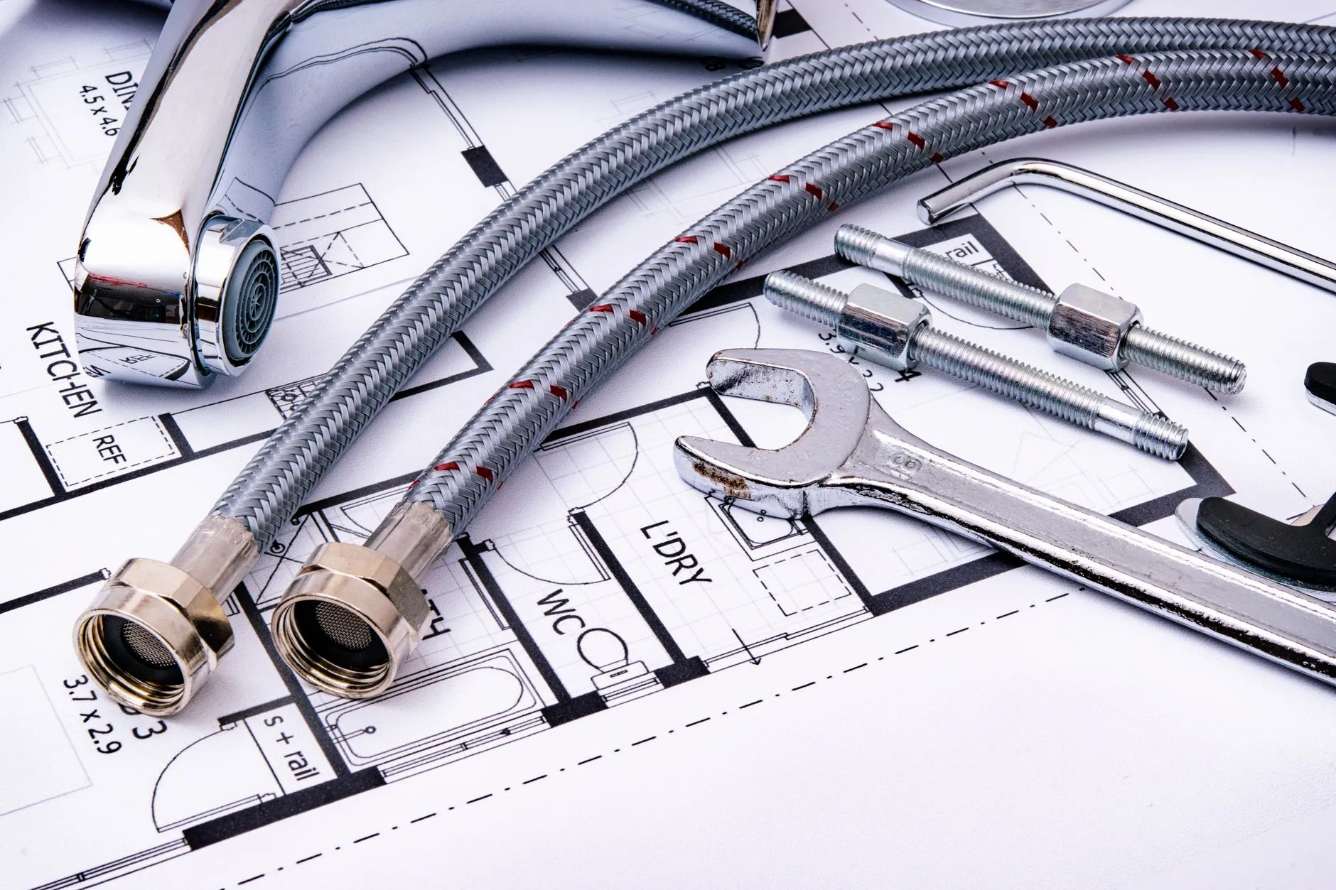 Close-up of plumbing tools and faucet on top of an architectural blueprint, perfect for hardware and construction themes